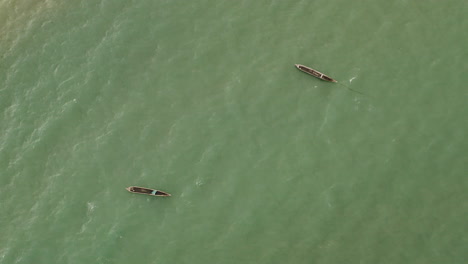 Aerial-shot-of-two-wooden-canoe-boats-anchored-near-the-beach-side-of-Dar-es-Salaam-city,-Tanzania