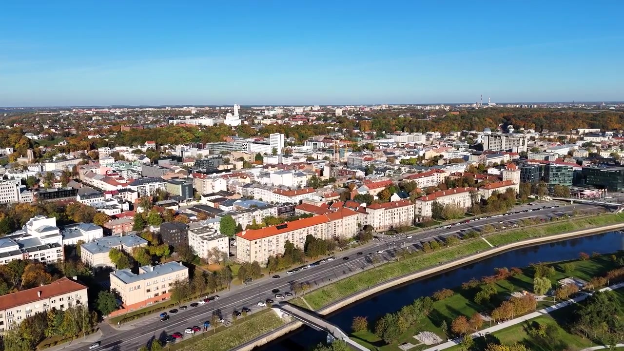 Widok z lotu ptaka przedstawiający tętniące życiem centrum Kowna w słoneczny jesienny dzień, z kolorowymi budynkami, krętymi drogami nadbrzeżnymi, rzeką Neris i bujnymi zielonymi parkami, Litwa
