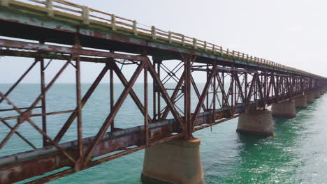 drone pullback along rusted metal support beams holding bridge and pipeline to broken gap