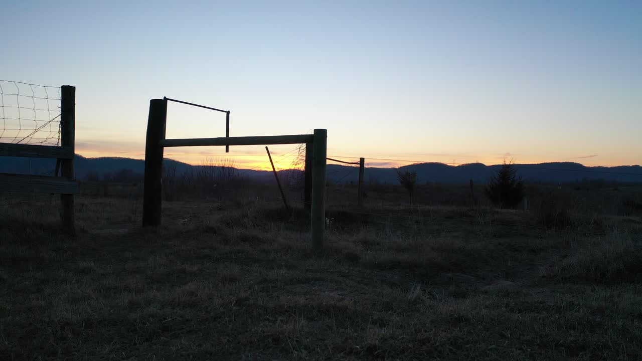 amanecer o atardecer sobre tierras de cultivo rurales con valla y puerta
