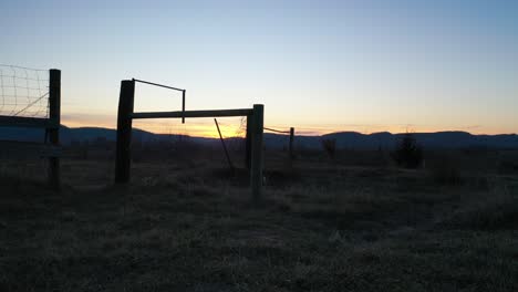 sunrise/sunset over rural farmland with fence and gate