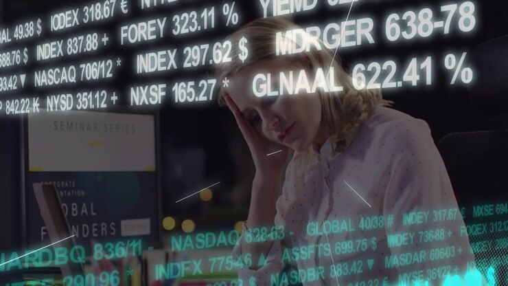 Reacting to scrolling tickers, woman shifting at desk touching laptop near monitor poster in blouse