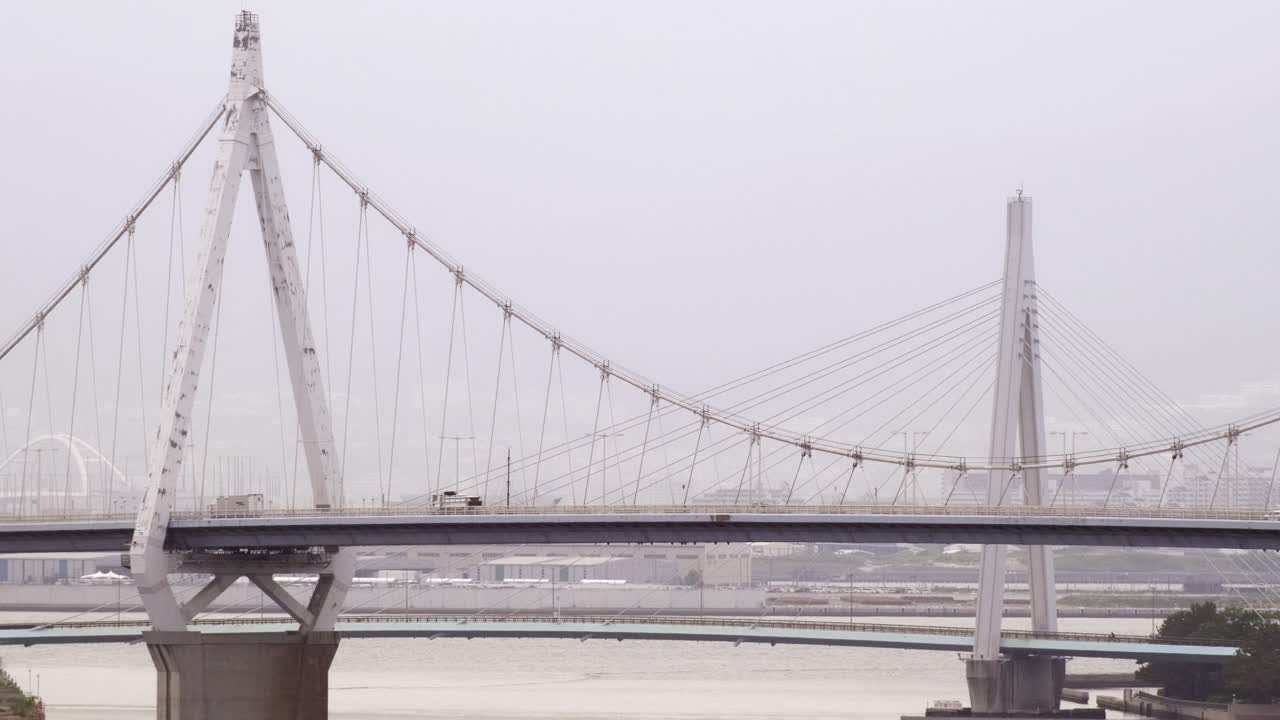 Wide shot of Konohana Bridge in Osaka, Japan, spanning Osaka Bay with Tsuneyoshi Ohashi in view under a hazy sky