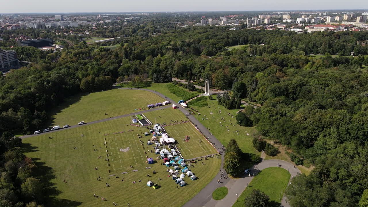 Drone shot of a Dog frisbee event in Poznan. Training dogs. Agility. Dog-Frisbee. Huge meadow with dogs catching a frisbee disc during summer. Tents and stalls on the grass field.