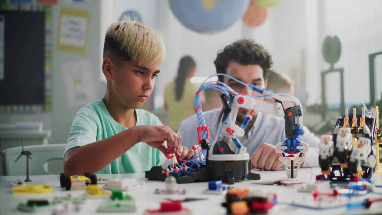 Talented Young Boy Sitting at the Desk Studying Robotic Arm Model