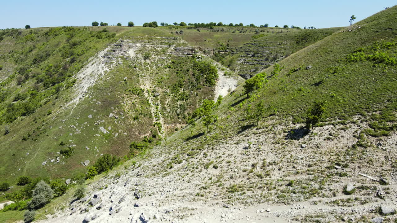 Aerial drone view of a valley with rocky hill slopes and greenery in Moldova