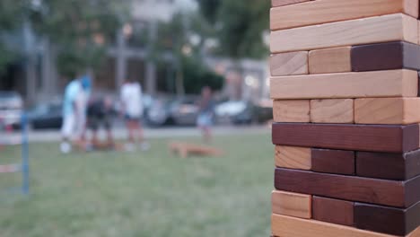 jenga de cerca con gente en el fondo jugando cornhole