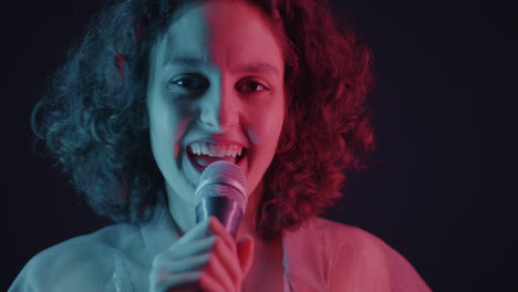 woman singing into a microphone with neon lighting