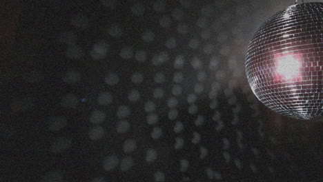 animación de un punto de luz rosa sobre una pelota de discoteca giratoria contra partículas blancas sobre un fondo negro.