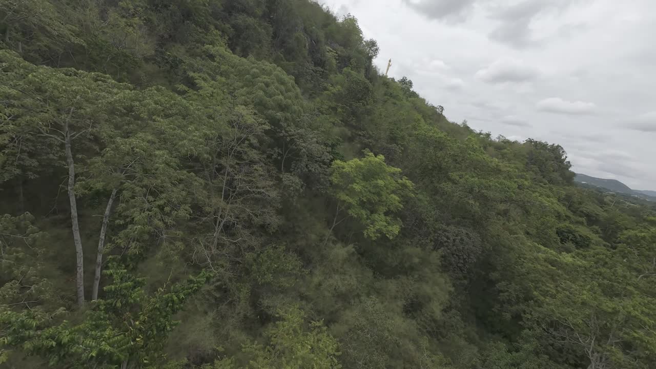 FPV aerial shot soaring over a lush green forest near the Kwai River in Kanchanaburi Province, Thailand