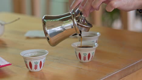 hand pouring lebanese black coffee into cup