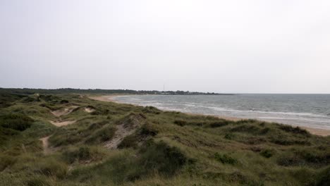 slow-motion shot of a swedish beach under an overcast sky. gentle waves roll onto the shore, and the muted colors of the sand, water, and sky create a tranquil yet moody coastal scene.