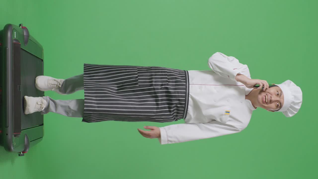녹색 화면 배경 스튜디오에서 는 동안 스마트폰으로 이야기하는 아시아 남성 요리사의 몸이 가득 차 있습니다.