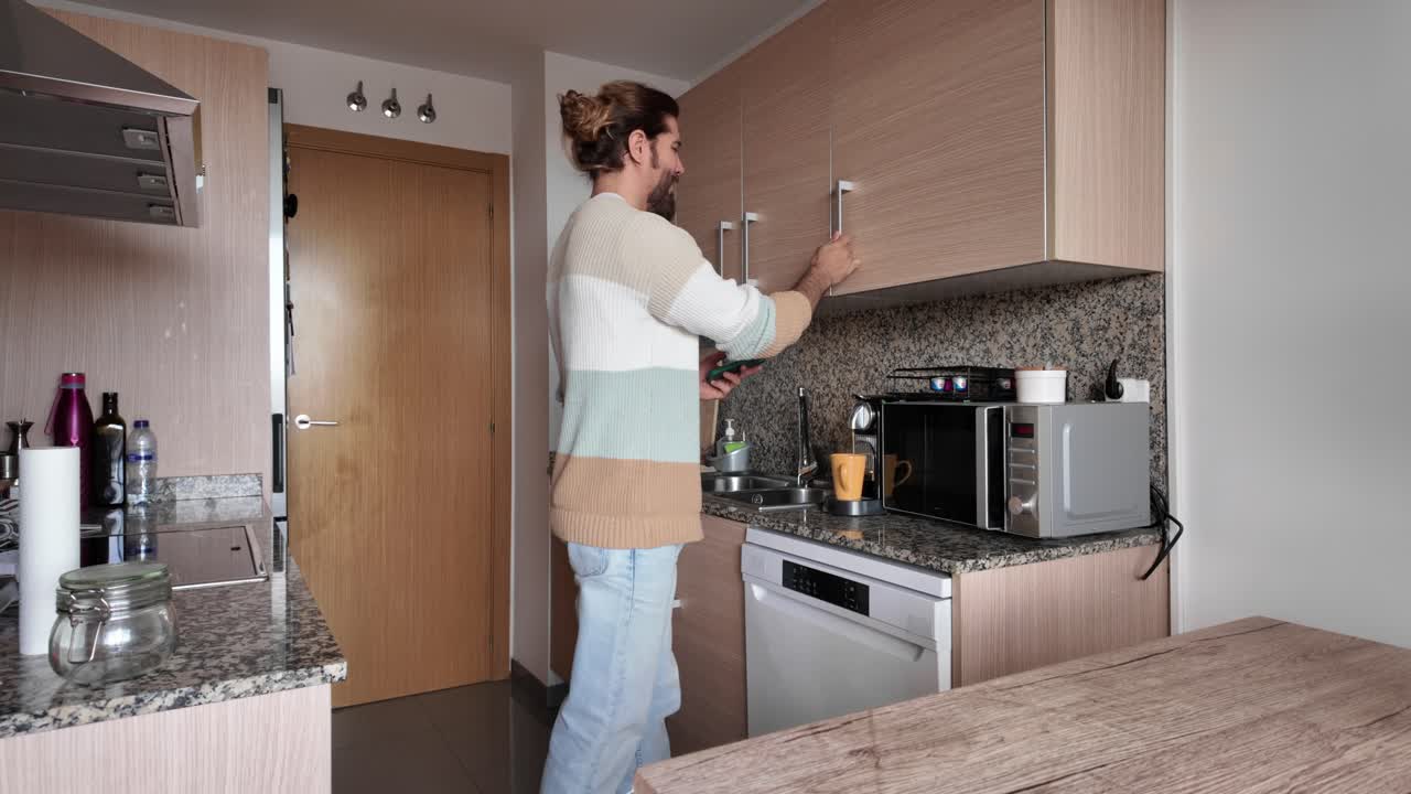 Un uomo in cucina che apre i mobili e usa gli elettrodomestici