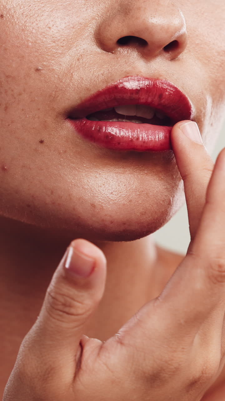 Mulher tocando seus lábios vermelhos e brilhantes e sorrindo de perto