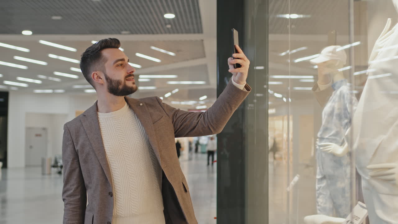 Uomo che fotografa un manichino in una vetrina
