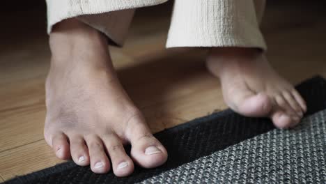 close up of person's bare feet on wooden floor with rug