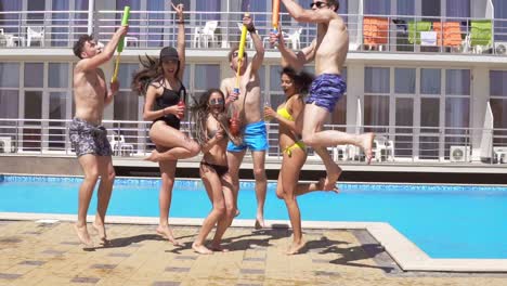 Happy-young-cheerful-friends-dancing-and-having-fun-at-the-pool.-Summertime-pool-party-with-water-guns-.-Slow-Motion-shot