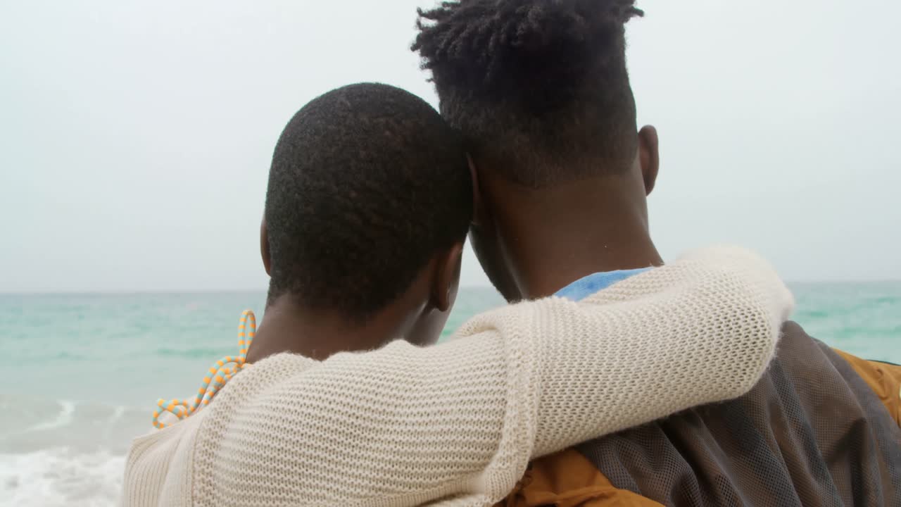 Rear view of African american couple embracing each other on the beach 4k