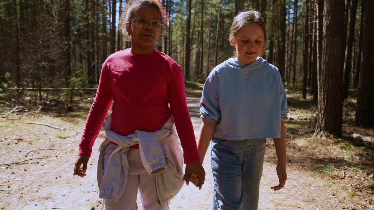 Two Girls Walking Hand-in-Hand in a Forest