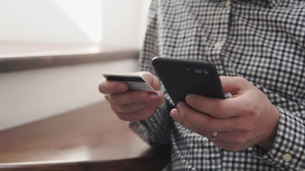 persona que utiliza un teléfono móvil y una tarjeta de crédito para el pago en línea