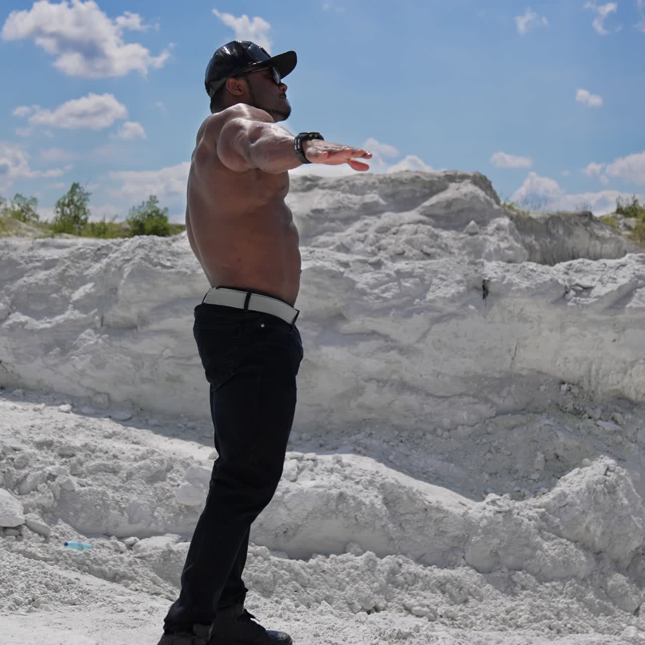 Muscular man with naked torso. Male bodybuilder with naked torso posing on the rock