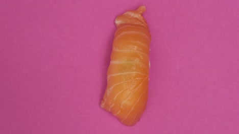 un rollo de sushi girando sobre un fondo rosado