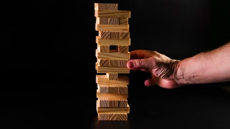 hand removing block from wooden tower