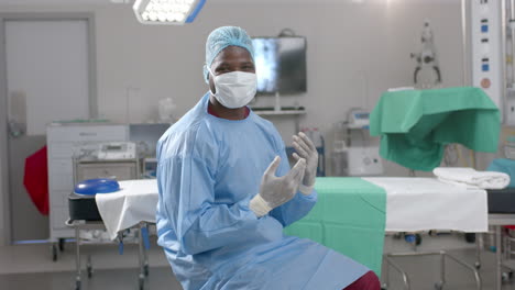 portrait of african american male surgeon wearing surgical gown in operating theatre, slow motion