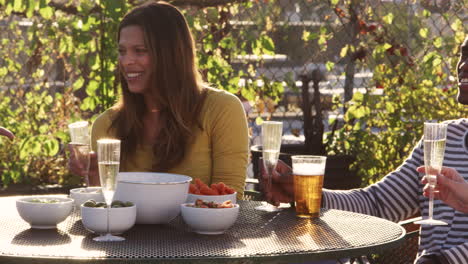 adult friends drinking at a table on roof terrace, pan shot