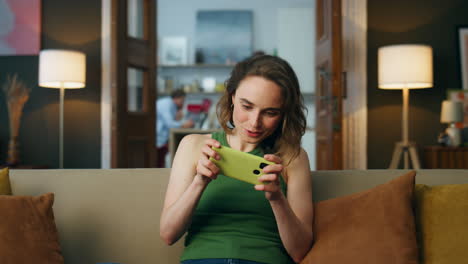 jugador enfocado jugando al teléfono móvil en casa en primer plano. mujer disfrutando de videojuegos