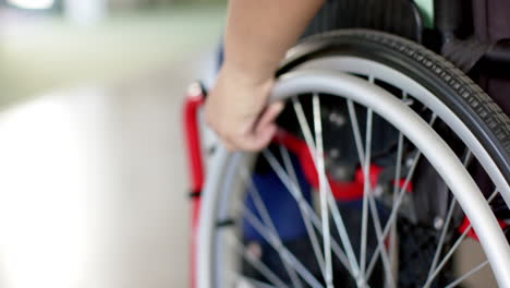 close-up of person using wheelchair, focusing on hand gripping wheel