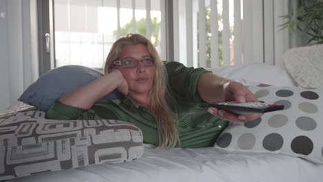 Attractive-blonde-woman-watching-TV-on-the-sofa-in-the-apartment