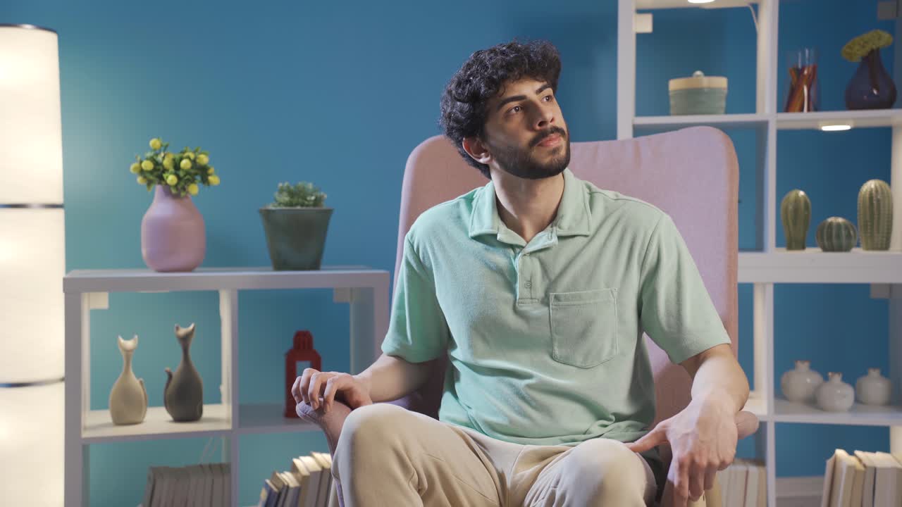joven sentado solo en casa en el sofá y esperando a alguien.