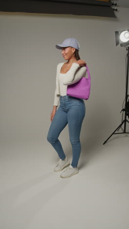 video vertical de una influencer femenina de redes sociales produciendo contenido generado por el usuario en un estudio de modelado variedad de diferentes bolsos de moda 1