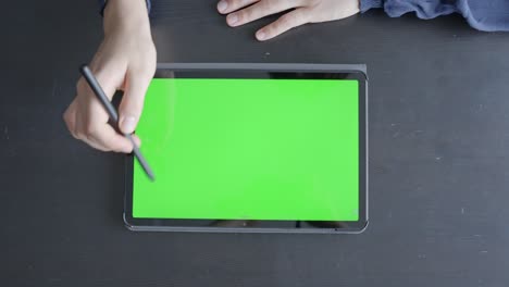 Green-Screen-Tablet-Liegt-Flach-Auf-Schwarzem-Schreibtisch,-Weibliche-Hände-Zeigen-An