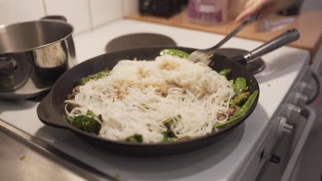 woman cooking wok with mushrooms, brocolli, chili, noodles, leek, suger peas and soy-2