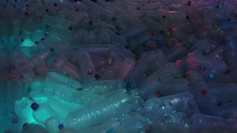 general shot of many empty water bottles with colored caps illuminated with colored light