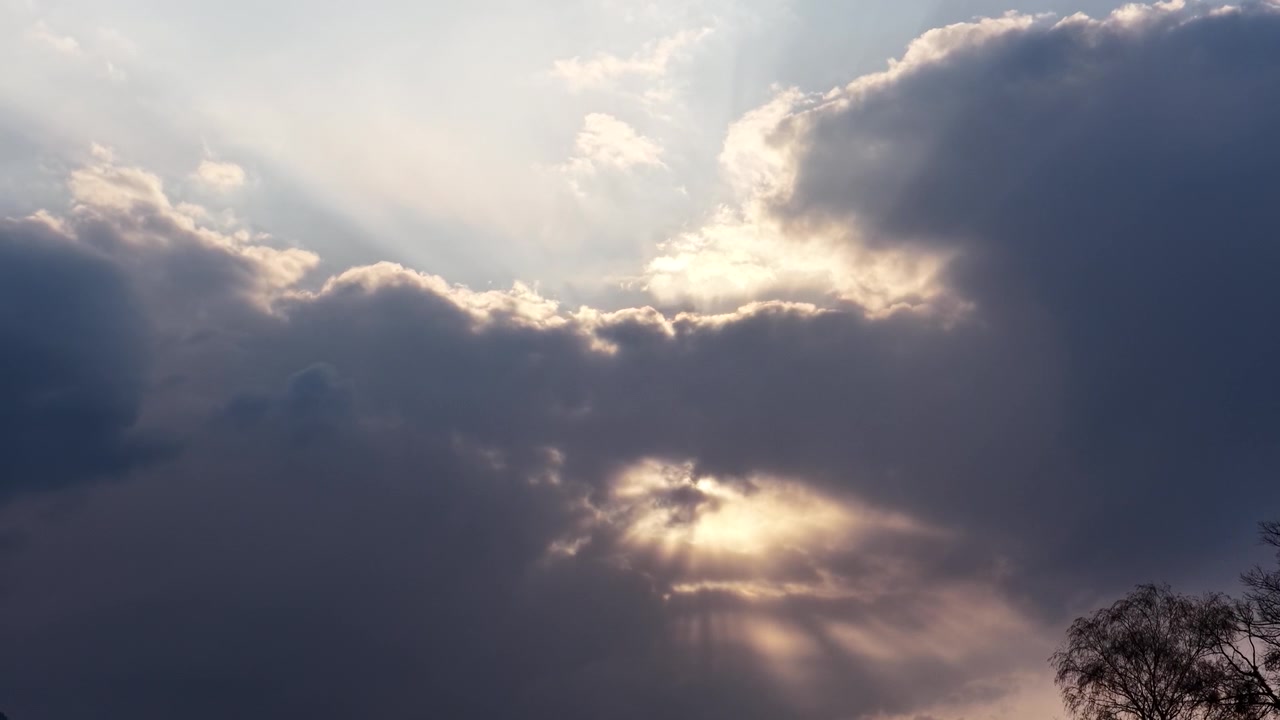 I raggi del sole si fanno strada attraverso nuvole imponenti, illuminando il cielo con una luce dorata e soffusa e creando una potente atmosfera di speranza, serenità e ispirazione