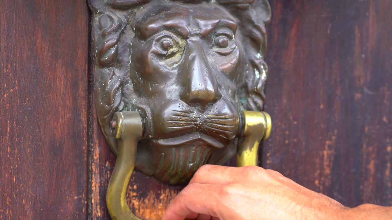 mano agarrando aldaba de la puerta. aldaba de león colonial