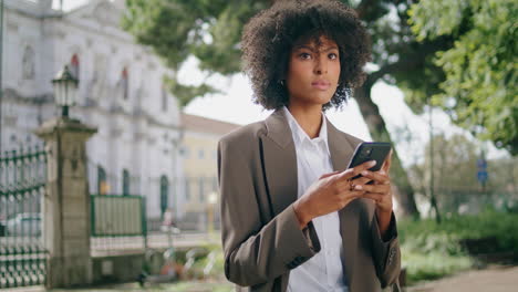 focused woman surfing smartphone standing in city park closeup. lady typing
