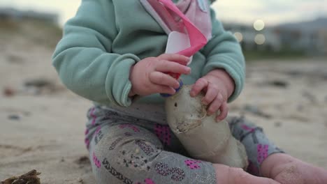 Nahaufnahme-Eines-Kleinen-Mädchens,-Das-Eine-Plastikflasche-Hält,-Während-Es-Am-Strand-Sitzt