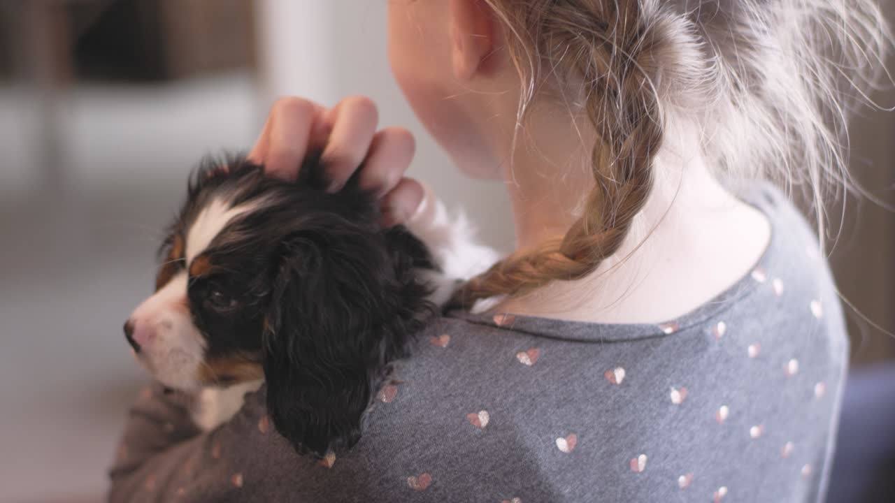 거실에서 사랑스러운 강아지를 들고 있는 어린 소녀의 어깨