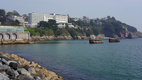 panning shot revealing the rugged coasts and cliffs of torquay and torbay with the rock arch london bridge arch in the distance