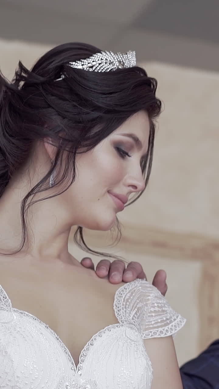 Primo piano al rallentatore di giovane sposo in abito con bouquet di rose che tocca la spalla scoperta della splendida sposa