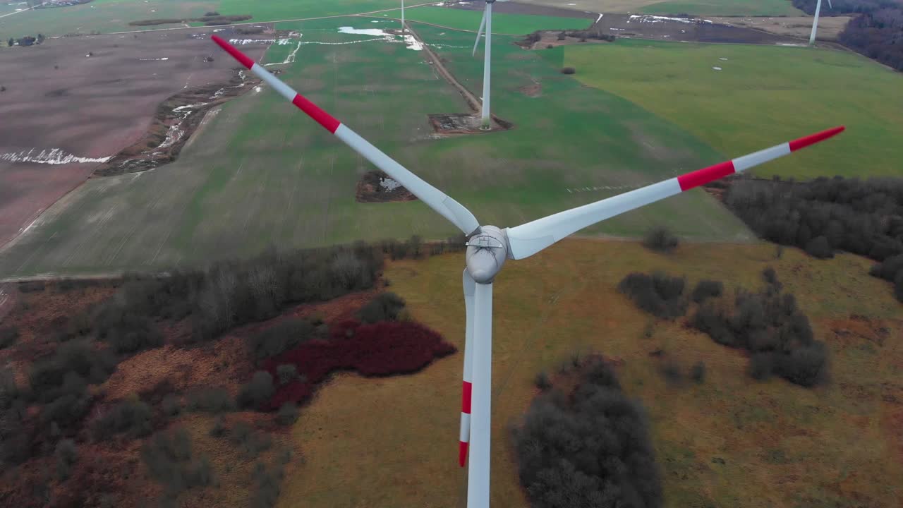 Zoom out drone view of renewable energy windmill farm rotate propeller with a horizon landscape background