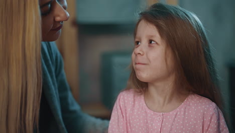 smiling mother puts pill onto tongue of little daughter