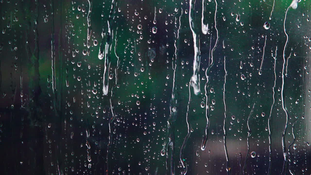 Raindrops Falling on a Window Pane with Blurred Green Background