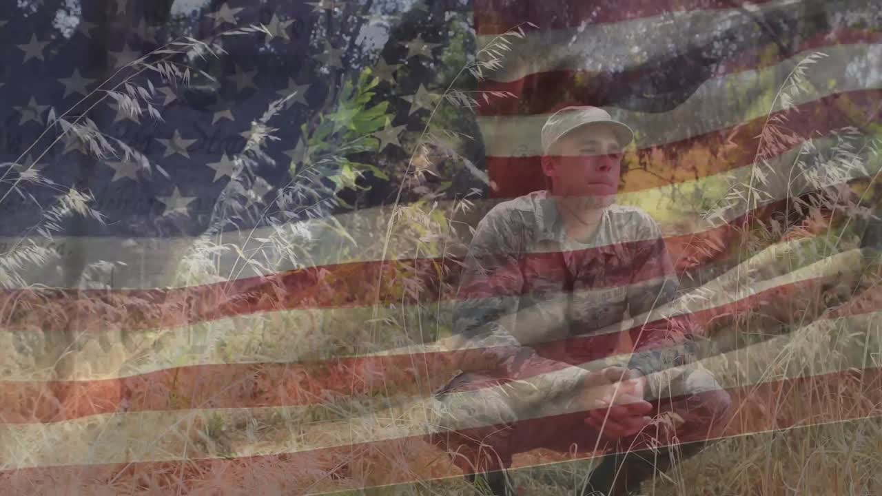 animación de la bandera de américa ondeando sobre el soldado caucásico mirando y sentado en posición de cuclilla