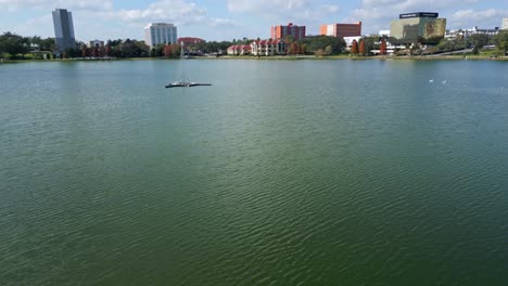 Drone-shot-over-Lake-Morton-in-downtown-Lakeland-Florida,-tilting-up-to-reveal-the-city-skyline